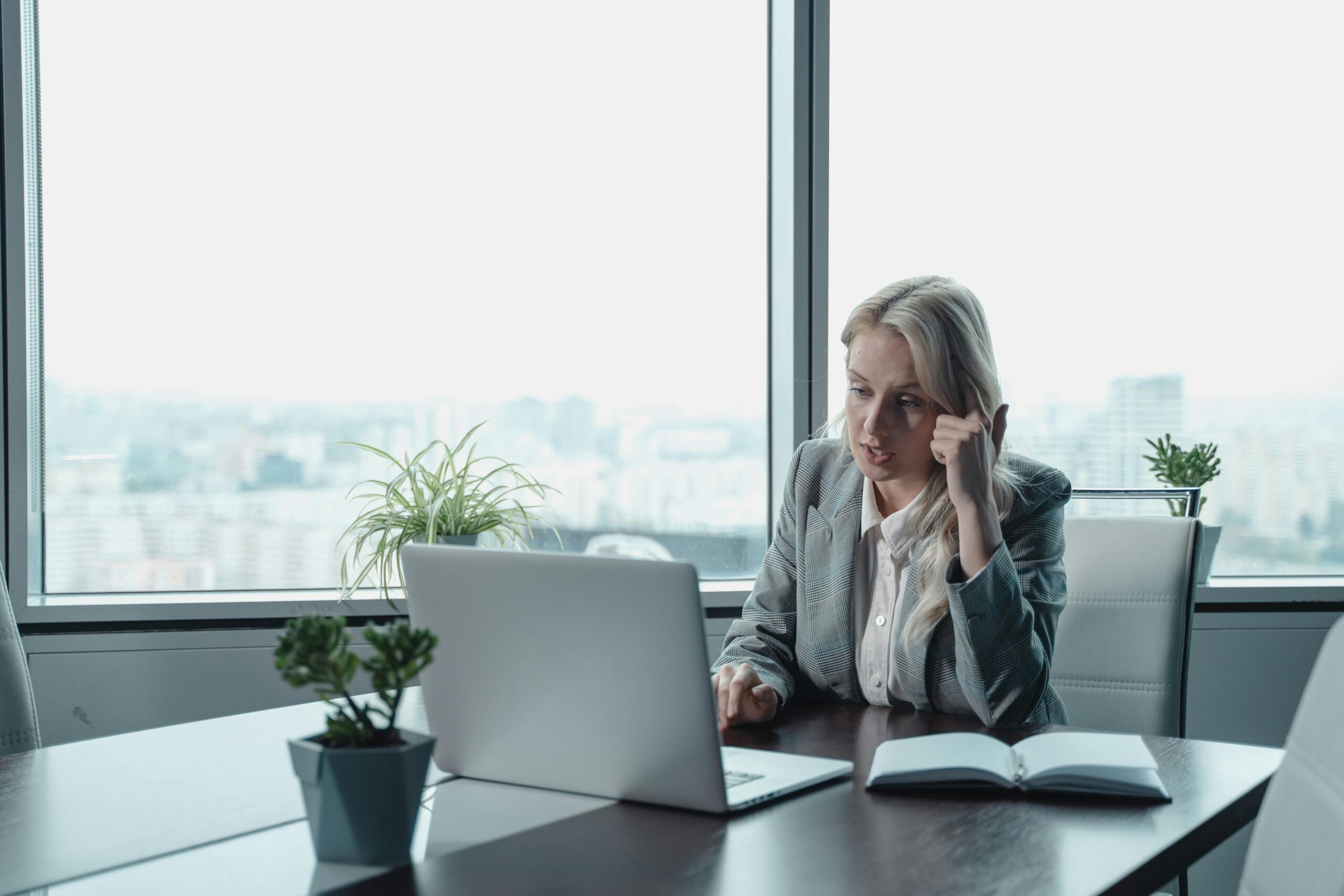 Professional woman engaged in a video meeting at a modern office desk with a laptop.